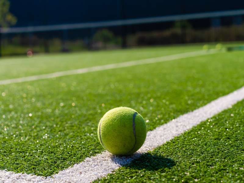 Tennis ball sitting on an artificial turf court