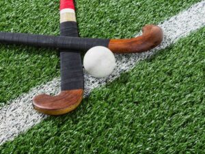 Hockey ball between two hockey sticks on artificial turf field